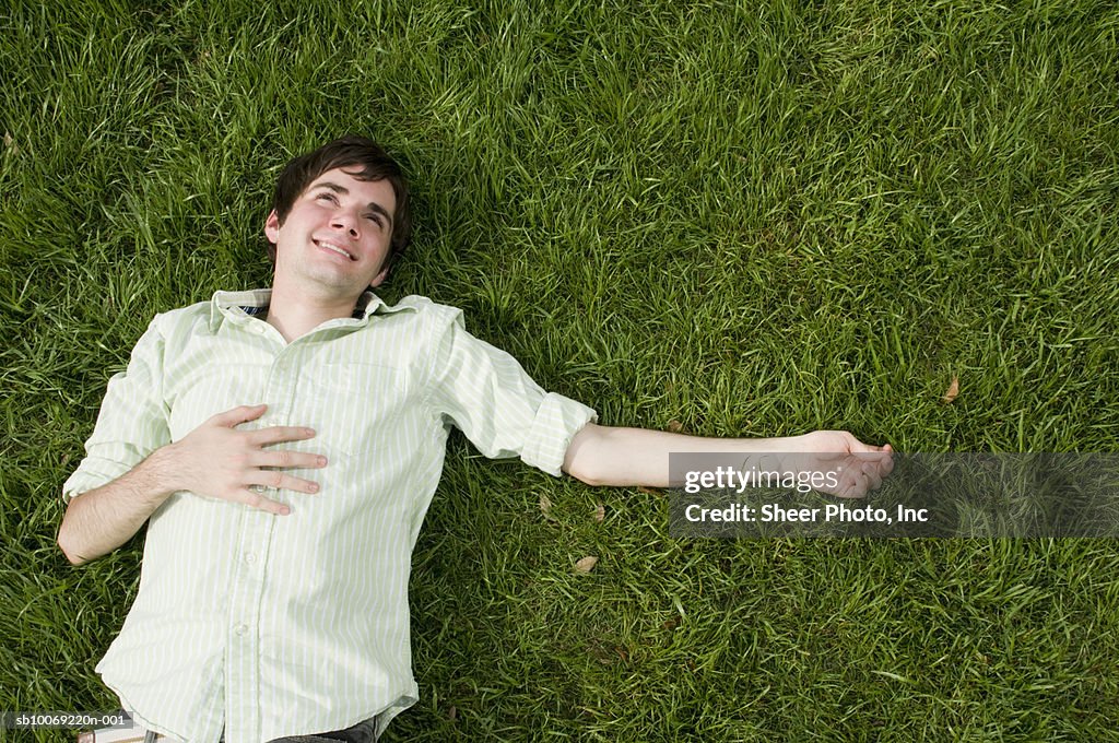 Young man lying in grass, high angle view