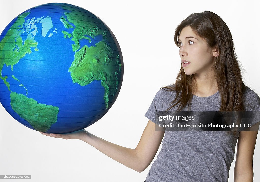 Teenage girl (16-17) carrying globe, portrait