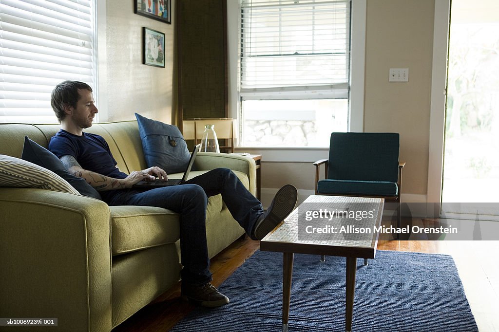 Man sitting on sofa using laptop