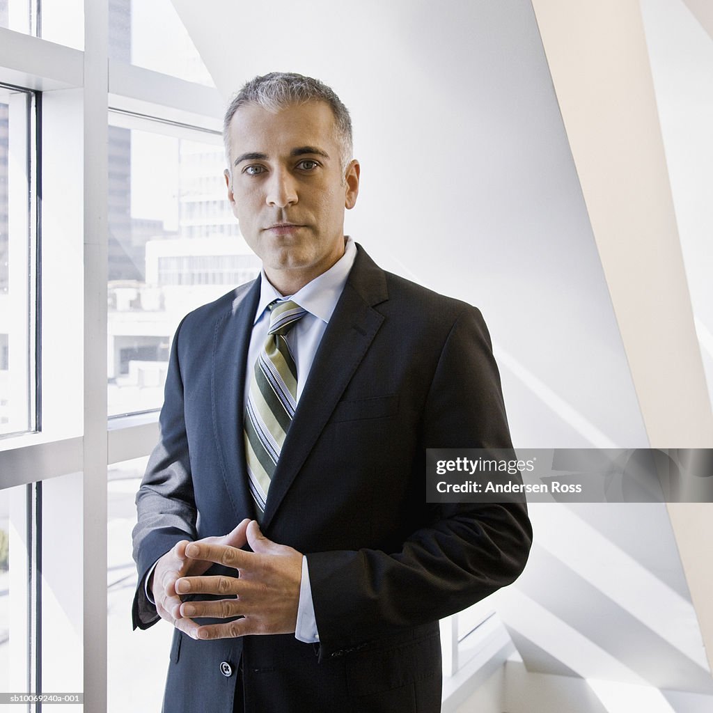 Business man standing by window, portrait