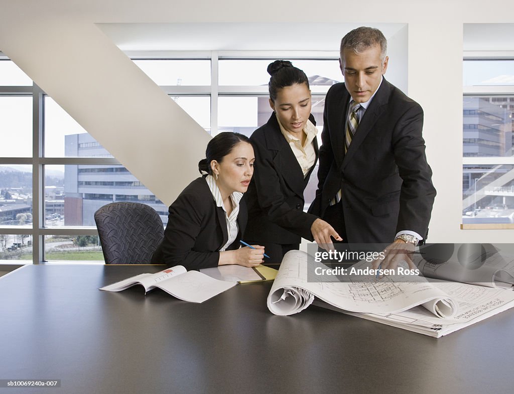 Three businesspeople discussing with blueprint