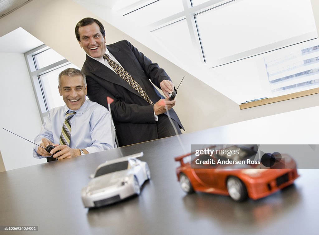 Two business men playing with remote control cars