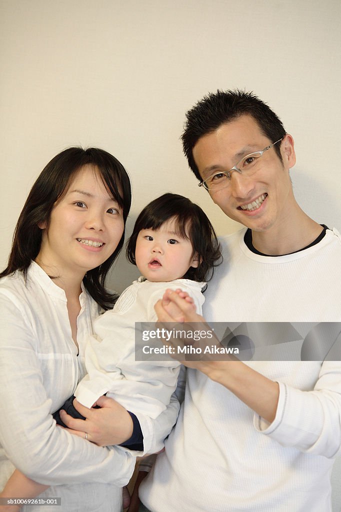 Parents holding baby girl (6-11 months) smiling, portrait, close up