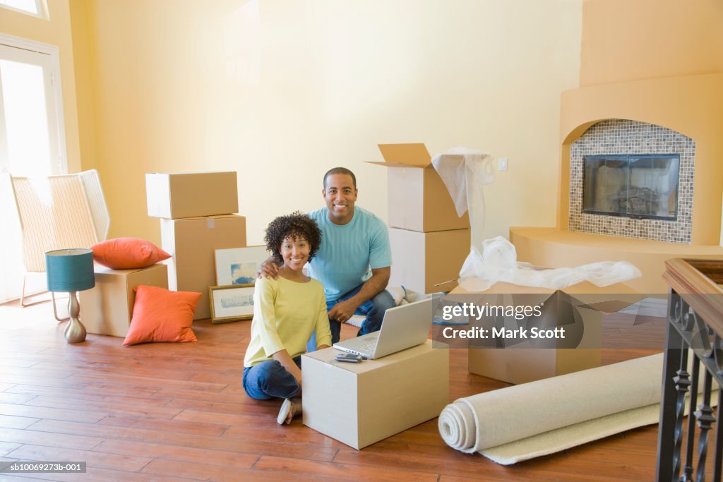 Couple between boxes in unfurnished room, portrait