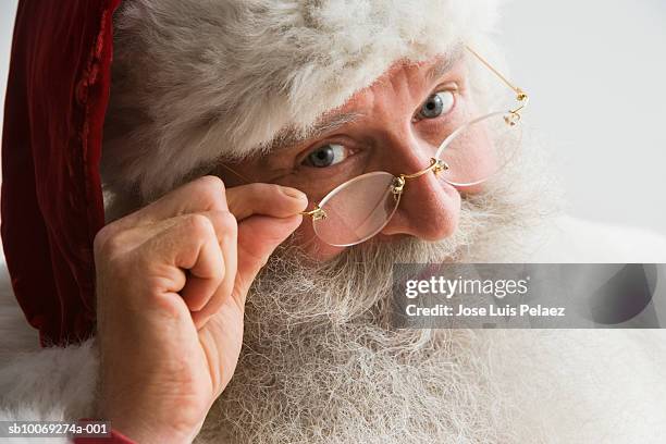 santa claus looking through spectacles, close-up - santa close up stock-fotos und bilder