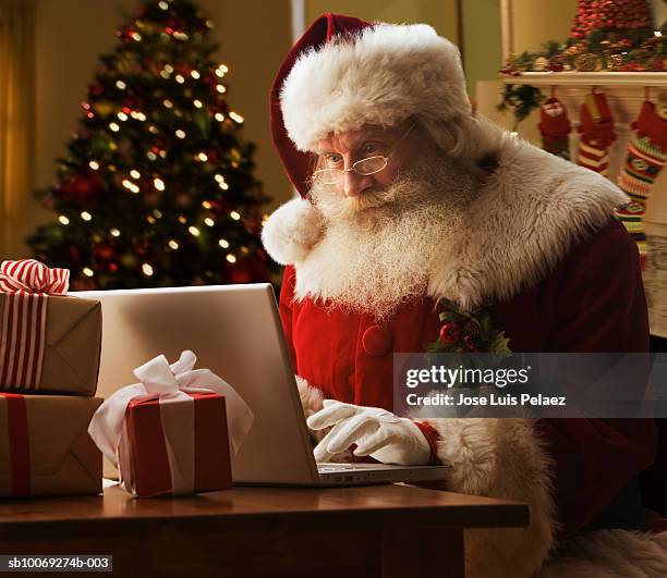 santa clause using laptop, close-up - santa close up stock-fotos und bilder