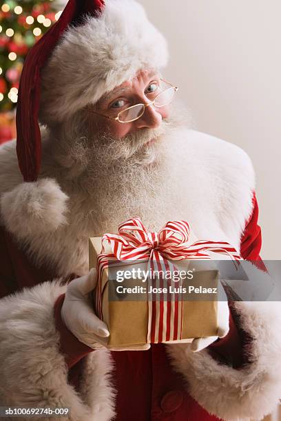 santa claus holding gift, smiling, portrait, close-up - santa close up stock-fotos und bilder
