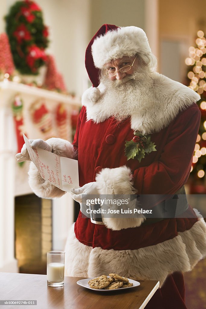 Santa Claus holding letter, smiling, portrait