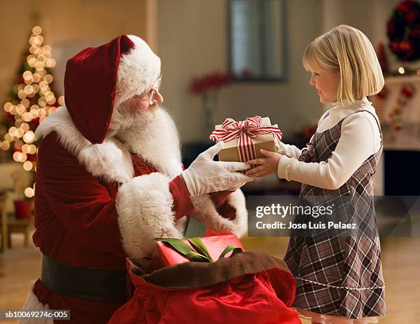 santa claus giving girl (4-5) gift, side view - santa giving out presents stock pictures, royalty-free photos & images