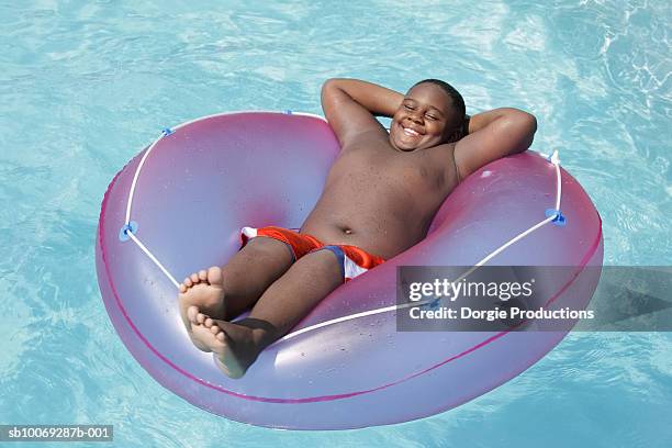 boy (10-11) floating on inflatable ring in pool, elevated view - its a boy stock pictures, royalty-free photos & images