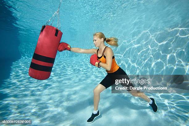 woman boxing in pool with punch bag, underwater view - boxe femme photos et images de collection
