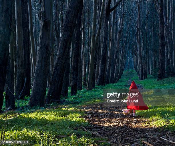 girl (4-5) dressed as little red riding hood in forest, rear view - rotkäppchen stock-fotos und bilder