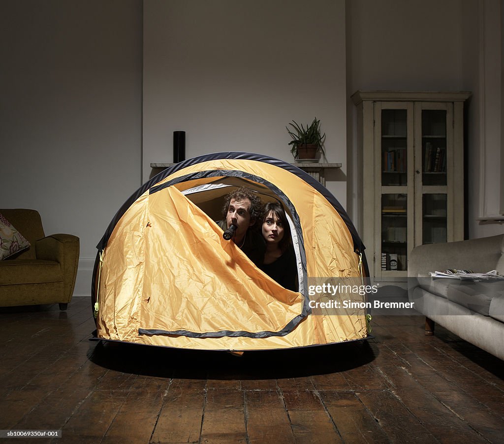 Couple peering from tent in living room