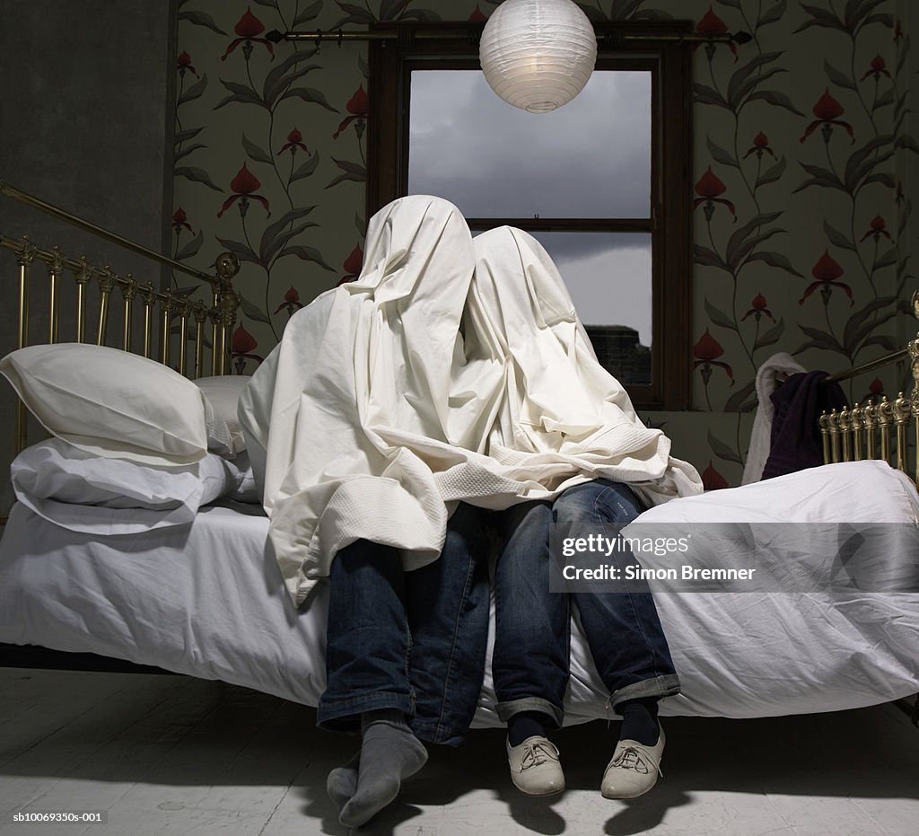 Couple se cachent sous la feuille sur lit