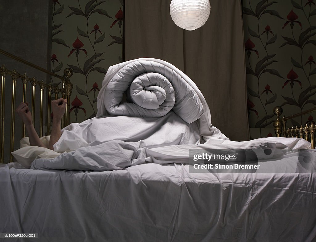 Person hiding under covers on bed