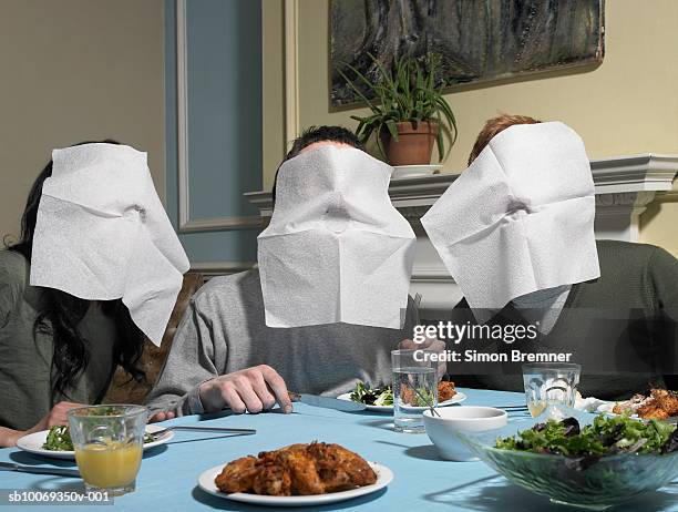 three people with napkins over faces, at dining table - eccentric stock pictures, royalty-free photos & images