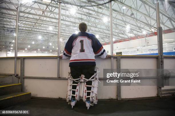 hockey goalie (14-15) looking at rink, rear view - hockey keeper stockfoto's en -beelden