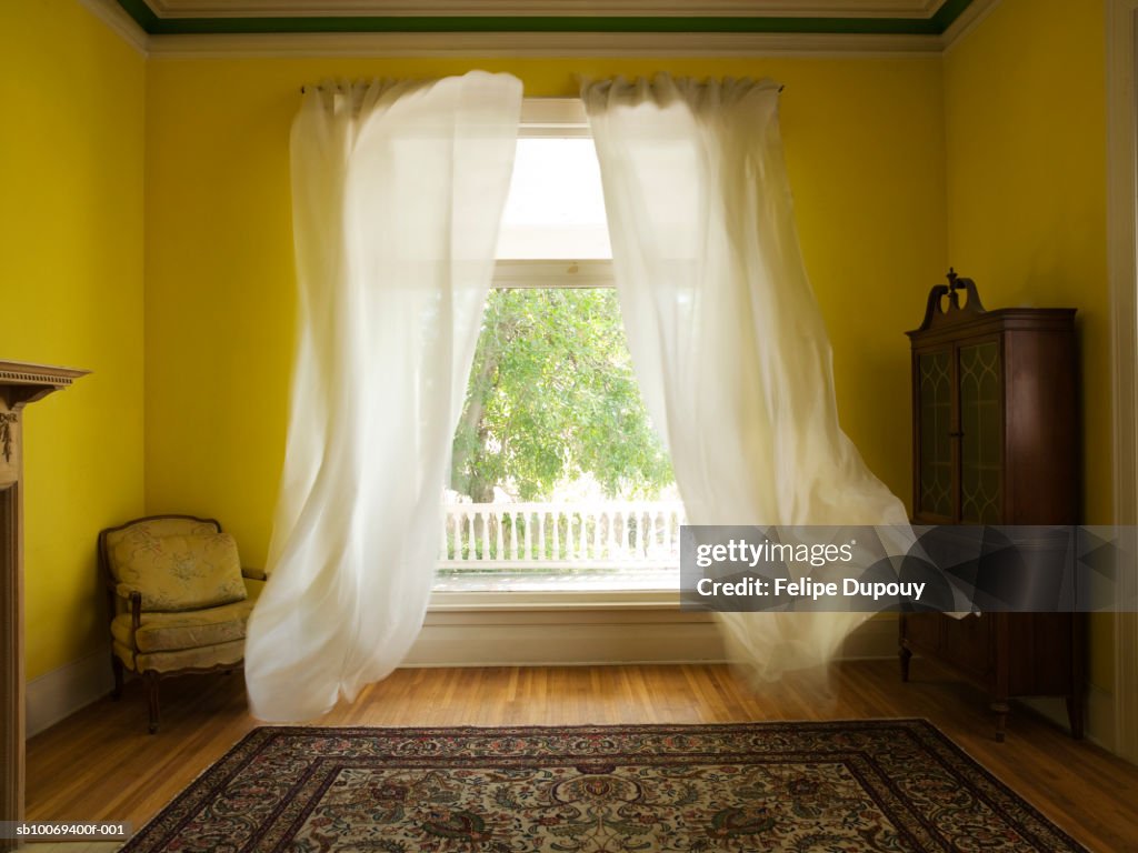 Room with curtains billowing at open window