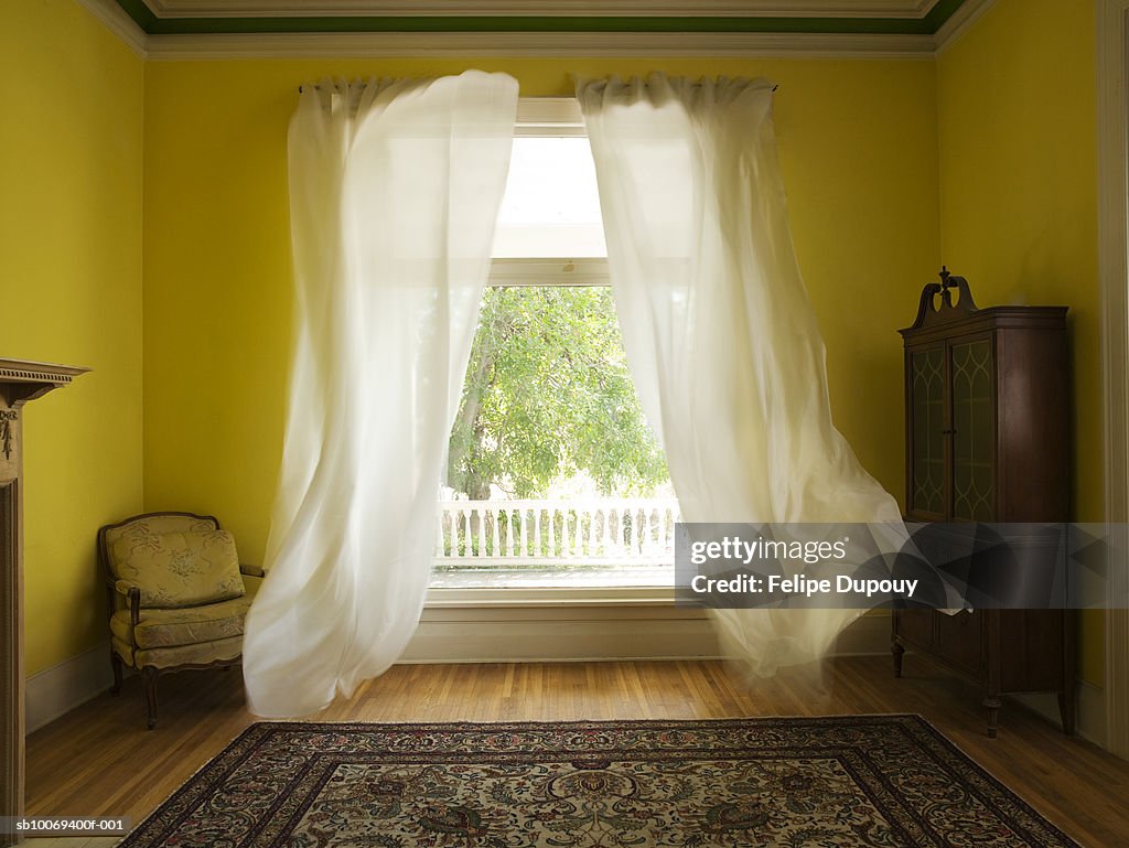 Room with curtains billowing at open window