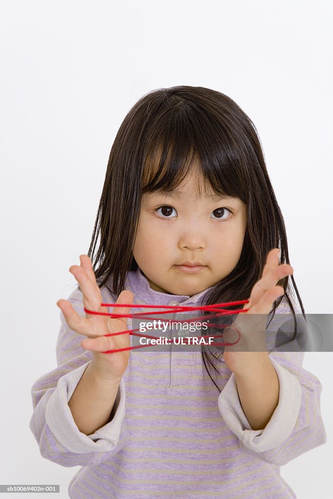 Studio portrait of girl (2-3) with cat's cradle