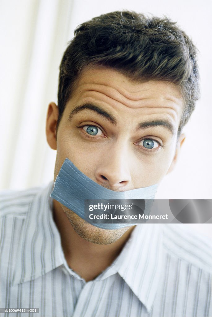 Man with sticky tape on mouth, portrait, close-up