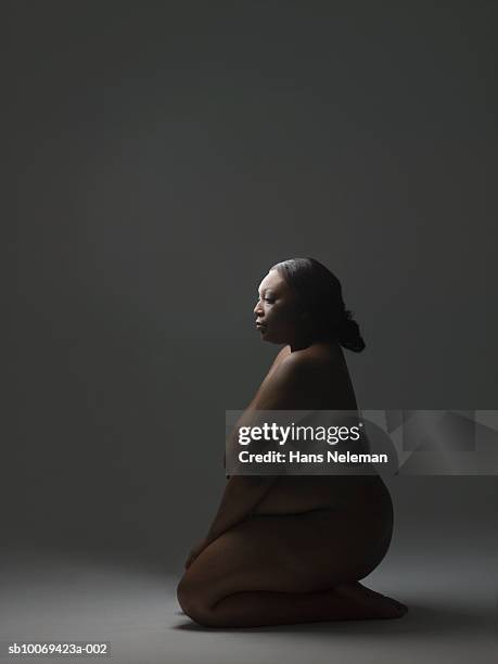 naked woman kneeling on floor, side view - weibliche brust fotos stock-fotos und bilder