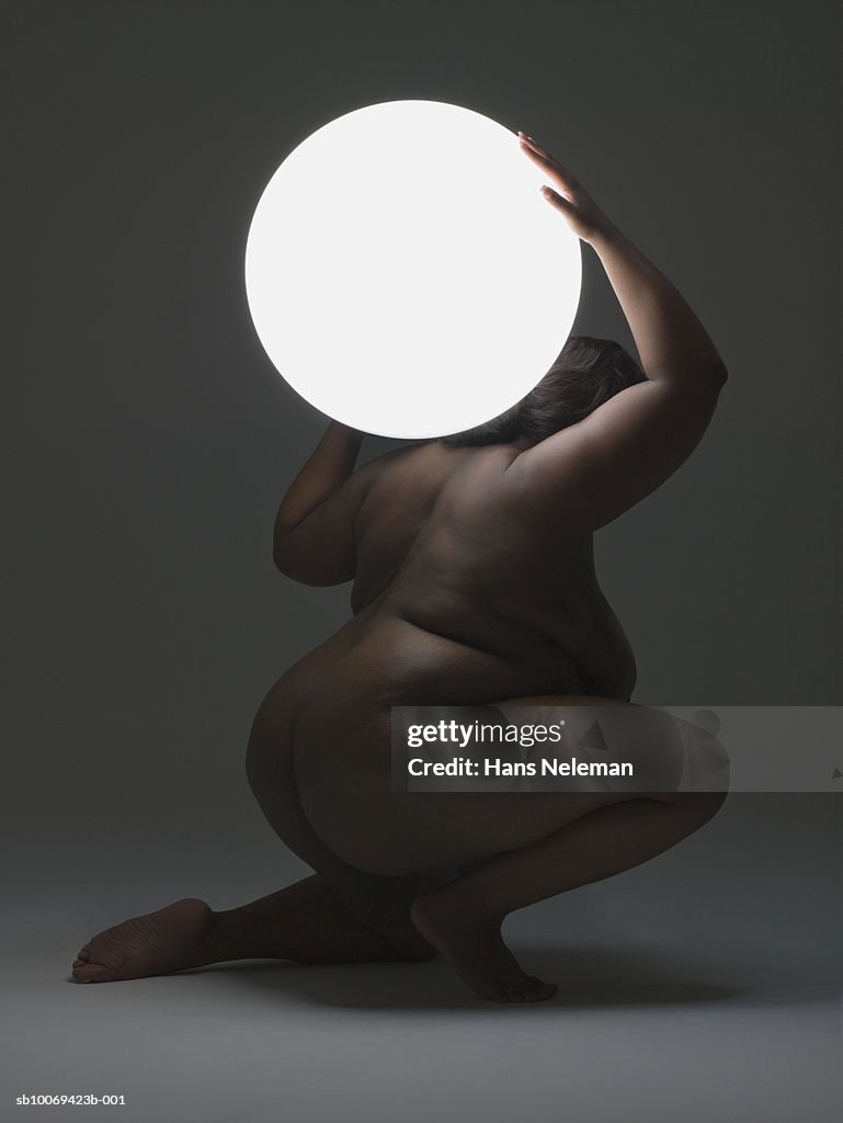 Naked woman carrying glowing sphere on shoulder