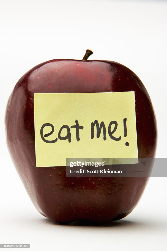 Red apple with adhesive note reading Eat Me