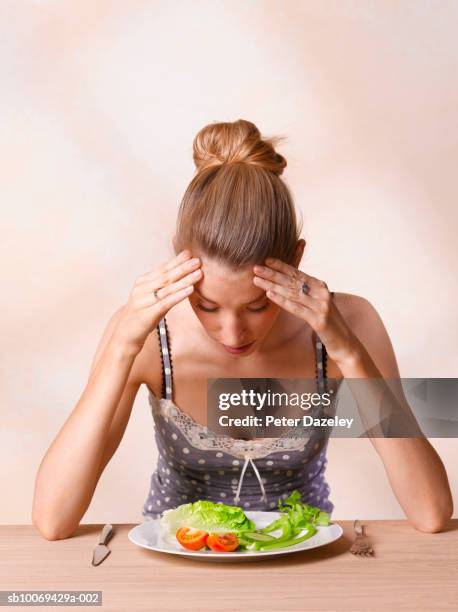 young woman looking at plate of salad - anorexia nervosa stock pictures, royalty-free photos & images