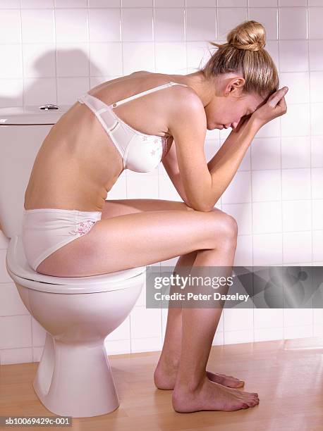 young woman sitting on toilet lid - food allergy stock pictures, royalty-free photos & images