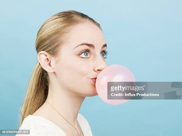 young woman blowing pink bubble gum bubble, studio shot - bubble ponytail stock pictures, royalty-free photos & images