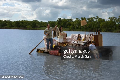 Family carrying house furniture in wooden raft