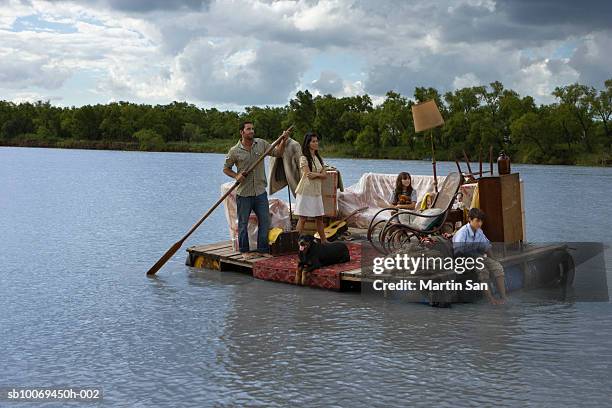 family carrying house furniture in wooden raft - ankle deep in water - fotografias e filmes do acervo