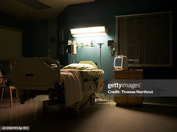 bed in darkened empty hospital room - krankenhaus stock-fotos und bilder