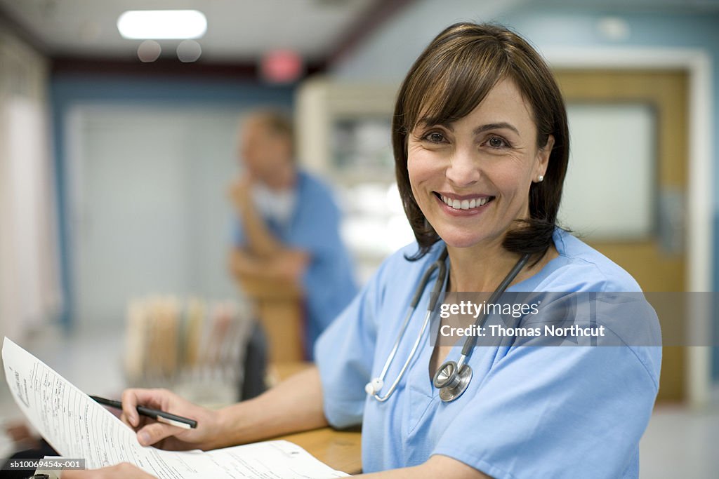 Female doctor holding medical records, smiling, portrait