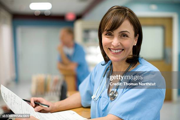 female doctor holding medical records, smiling, portrait - image stock pictures, royalty-free photos & images