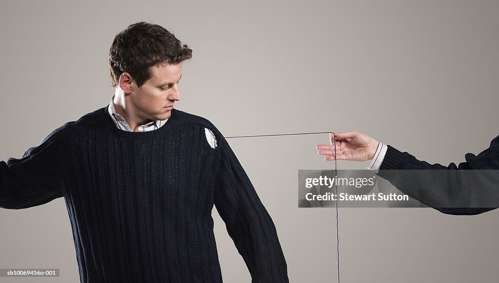 Person unraveling mans sweater, indoors