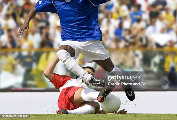 men playing soccer in stadium, one tackling other - defesa jogador de futebol imagens e fotografias de stock