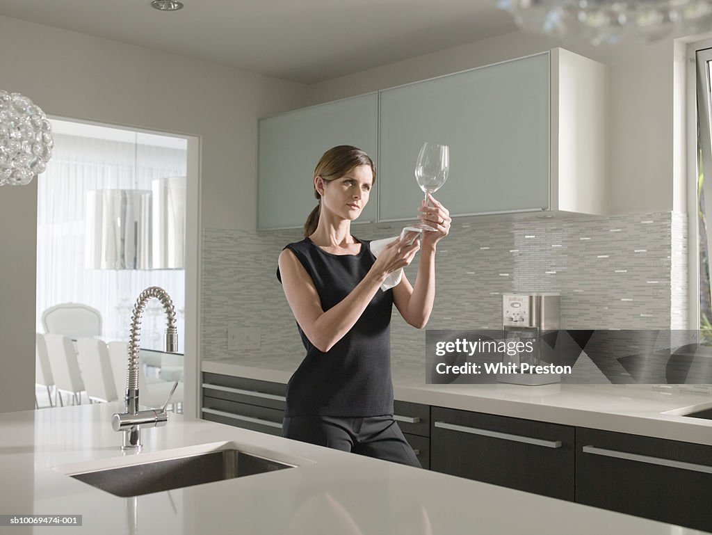 Woman cleaning wine glass in kitchen