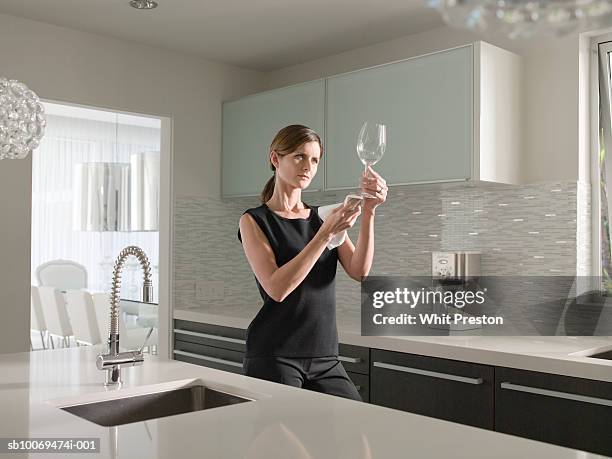 woman cleaning wine glass in kitchen - clean wine glass stock pictures, royalty-free photos & images