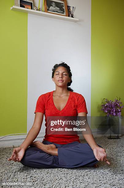 young woman sitting in lotus position in living room - yoga rug photos et images de collection