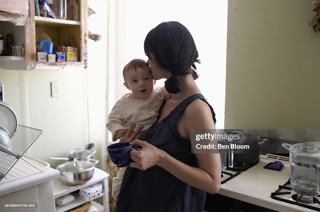 Mother kissing baby boy (6-11months) in kitchen