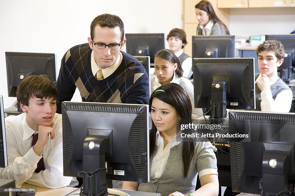 Teacher with school children (14-19) working in computer lab