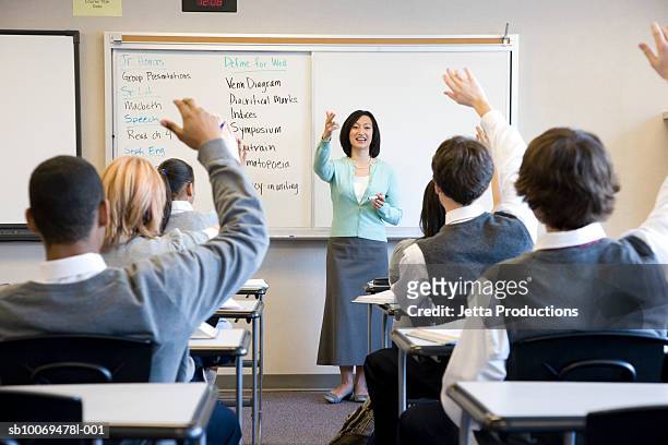 school children (14-18) raising hands in class - school uniform stock pictures, royalty-free photos & images