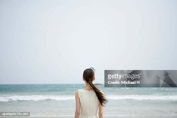 young woman looking at sea, rear view - black hair back stock pictures, royalty-free photos & images