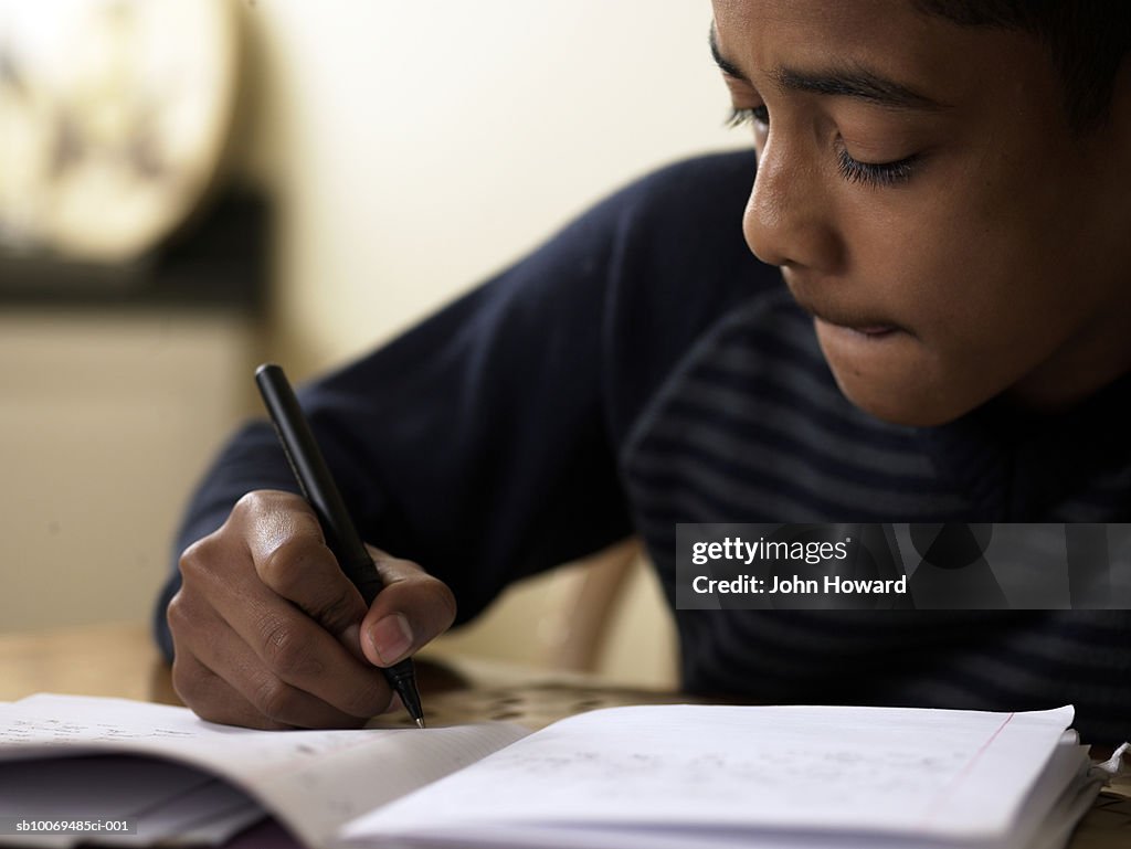 Close-up of boy (12-13) doing homework at desk