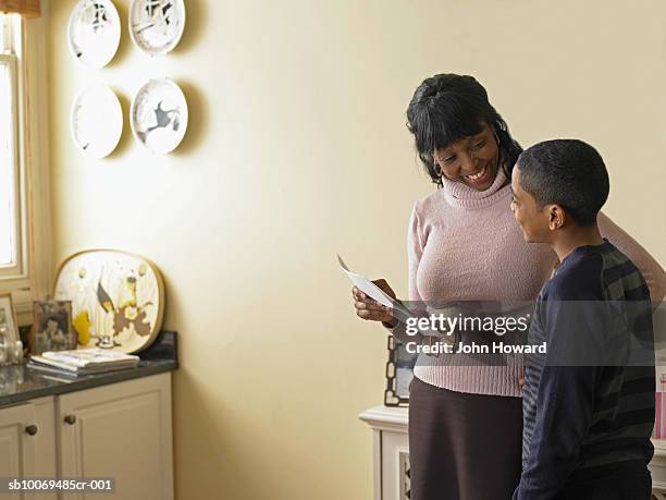 mother and son (12-13) holding school report card - john good stock pictures, royalty-free photos & images