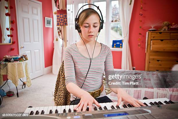 girl (12-13) wearing headphones and playing electric piano - 12 13 jaar stockfoto's en -beelden