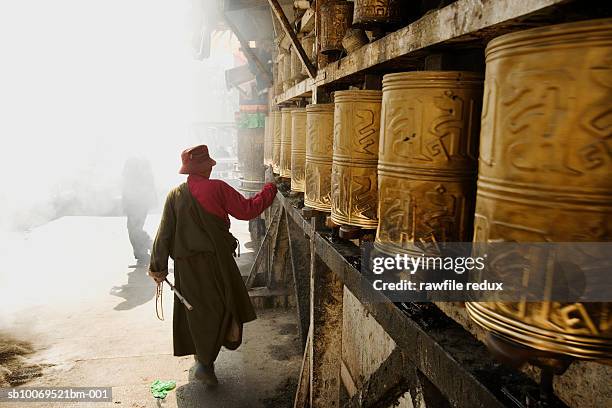 tibet, lhasa, pilgim rolling prayer wheels outside temple - tibet stock pictures, royalty-free photos & images