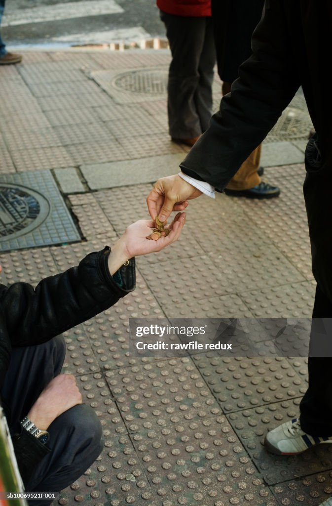 Man giving change to beggar, low section